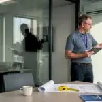Energy assessor checks HVAC in glass-walled office