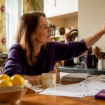 Woman adjusting smart thermostat in living room