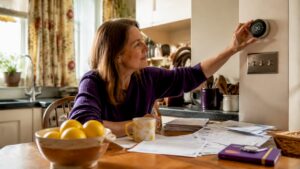 Woman adjusting smart thermostat in living room