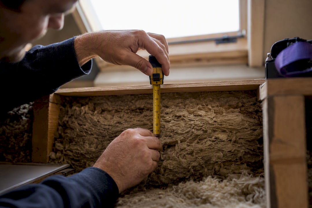 Installer measuring loft insulation depth