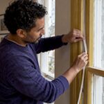 Homeowner fitting draught proofing to sash window