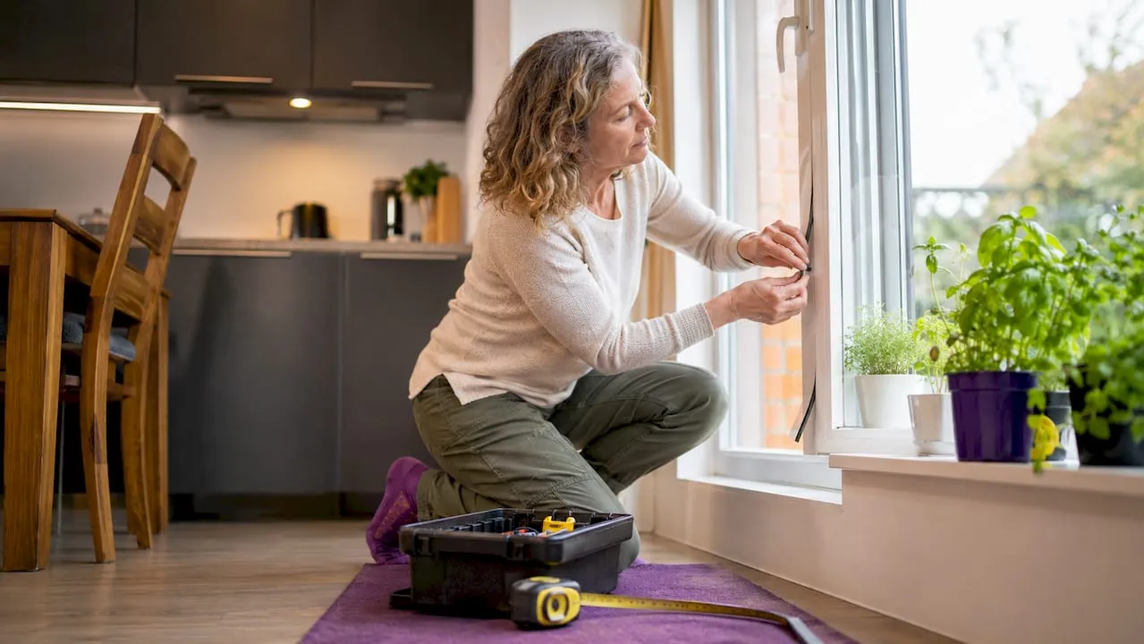 Woman draught-proofing home window