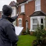 Energy assessor measuring house wall for EPC survey