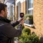 Energy assessor scanning house exterior with thermal camera