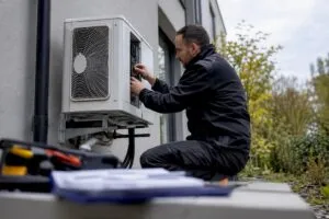 Assessor inspecting heat pump outside home