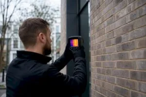 Energy assessor measuring residential wall insulation