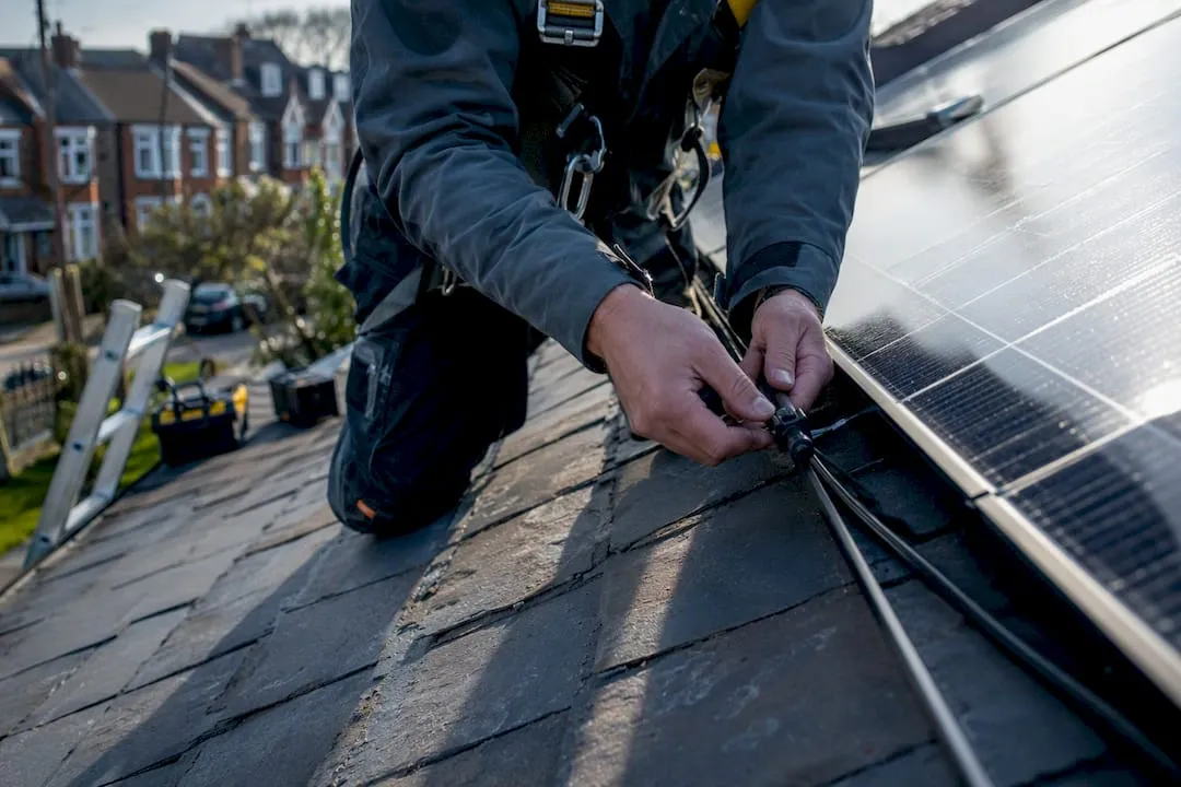 Technician wiring solar panels on roof