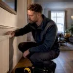 Assessor inspecting radiator in London flat