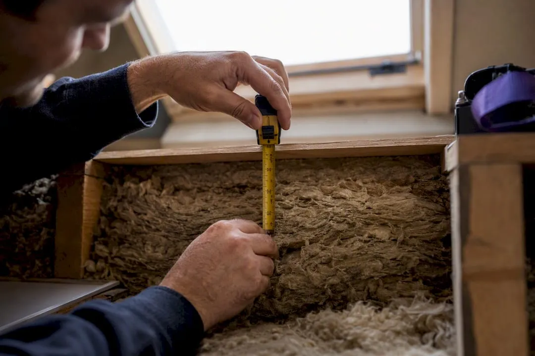 Installer measuring loft insulation depth