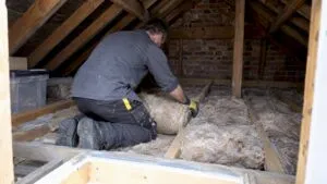 Installer laying loft insulation between joists
