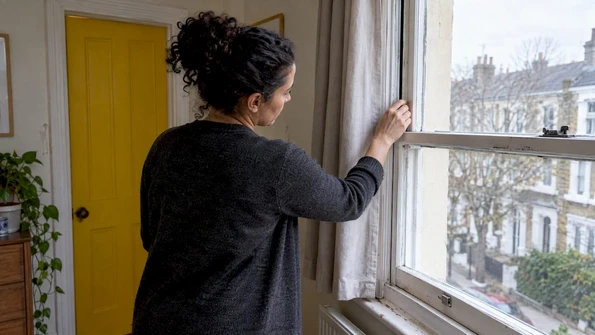 Landlord checking draught proofing around window