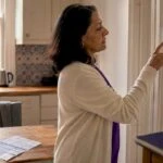 Woman adjusting thermostat in London home