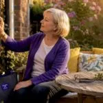 Senior woman adjusting thermostat at home